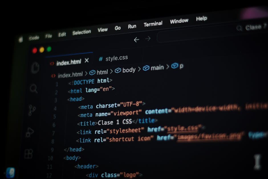 A person typing on a laptop with a dark-themed code editor open on the screen, displaying lines of multicolored programming code. The individual has light skin and is seated at a desk, with their righ